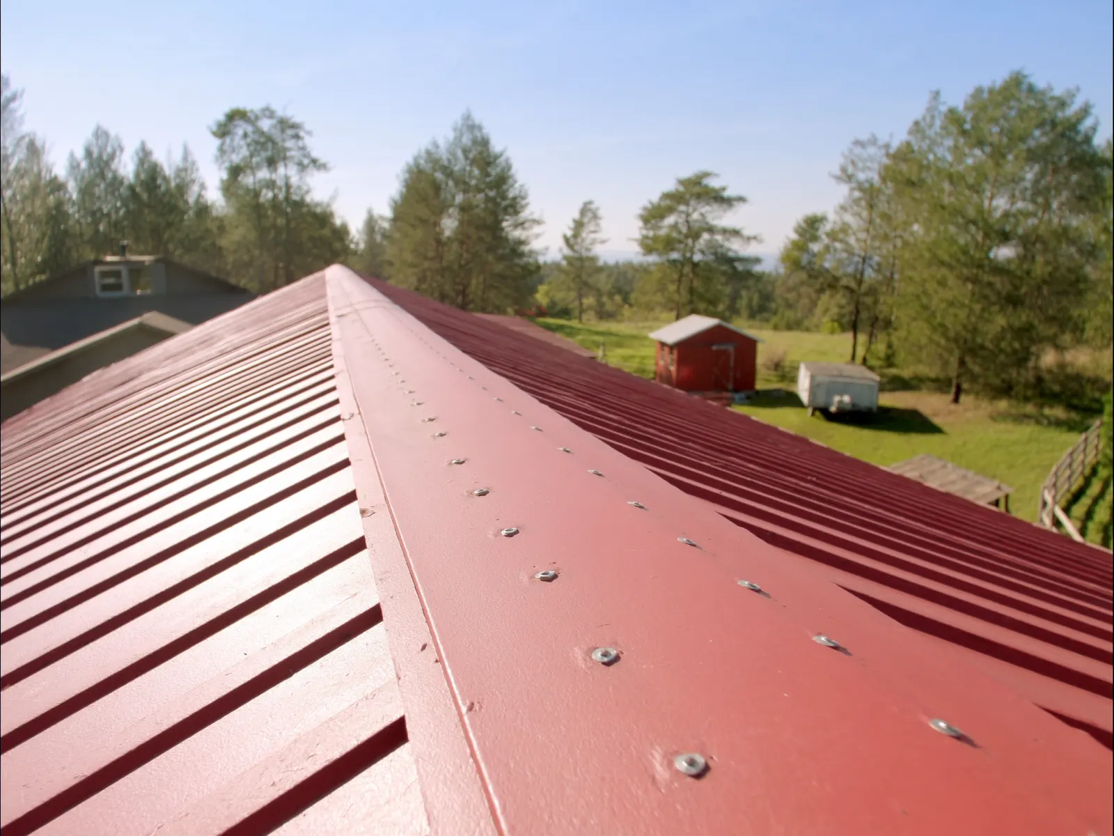 Red exposed-fastener ribbed metal panel roof on a country home