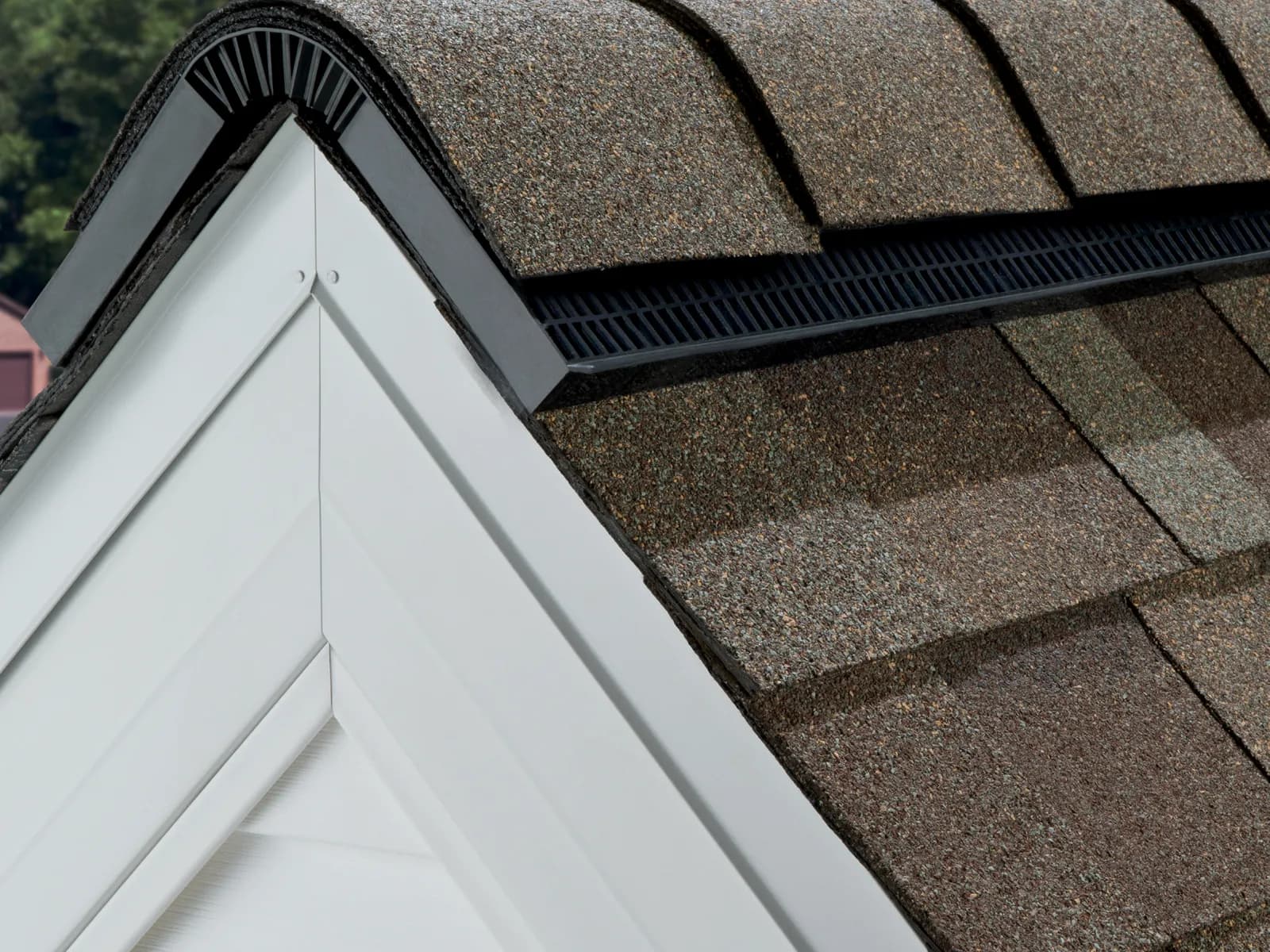 Black shingle-over ridge vent installed at the peak of an architectural shingle roof
