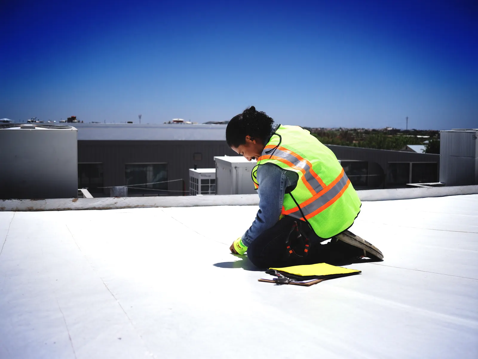 Technician inspecting a white commercial flat roof
