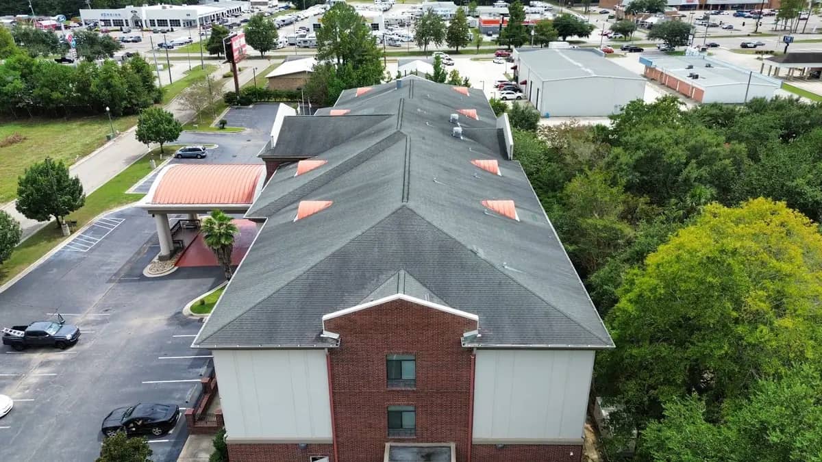 The Holiday Inn Express roof from the front, shingles weathered and lifted across the main slopes
