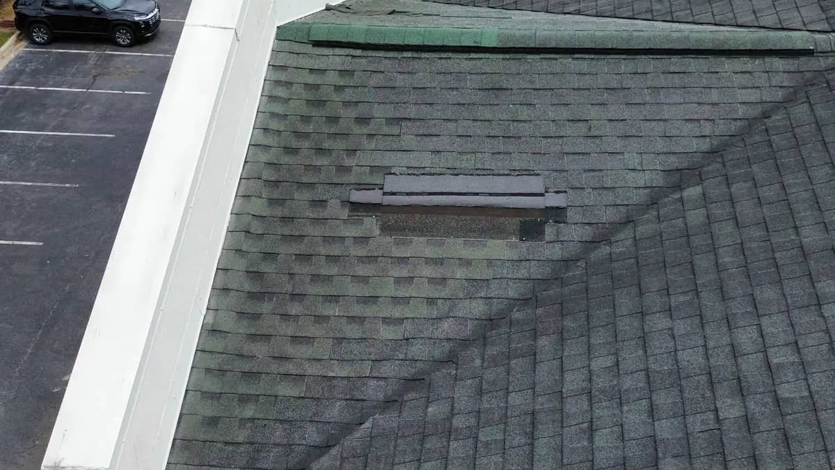 Wind damage on a slope of the Picayune hotel roof, with a course of shingles torn away