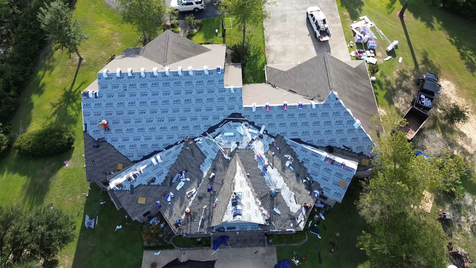 Drone view of a Southeast Roofing crew re-roofing a home in Purvis, Mississippi, synthetic underlayment down across the deck