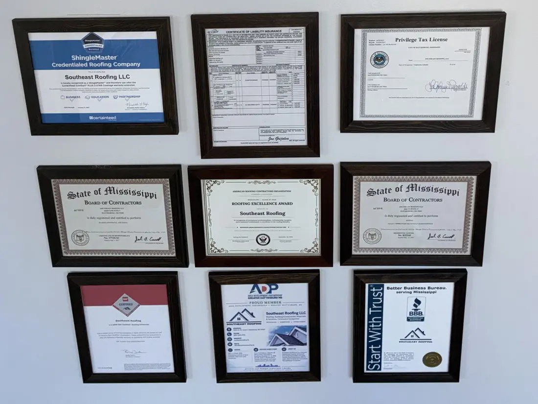 Nine framed certificates on the office wall, among them the Mississippi State Board of Contractors residential and commercial licenses, the CertainTeed ShingleMaster credential, the GAF Certified Contractor certificate, BBB accreditation and chamber membership.