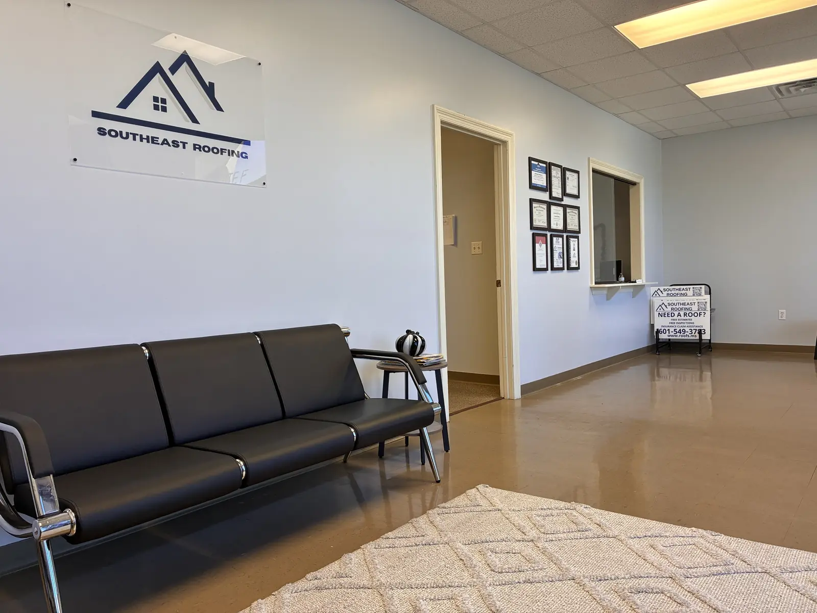 The waiting area inside Southeast Roofing's Hattiesburg office, with the company sign above the bench.